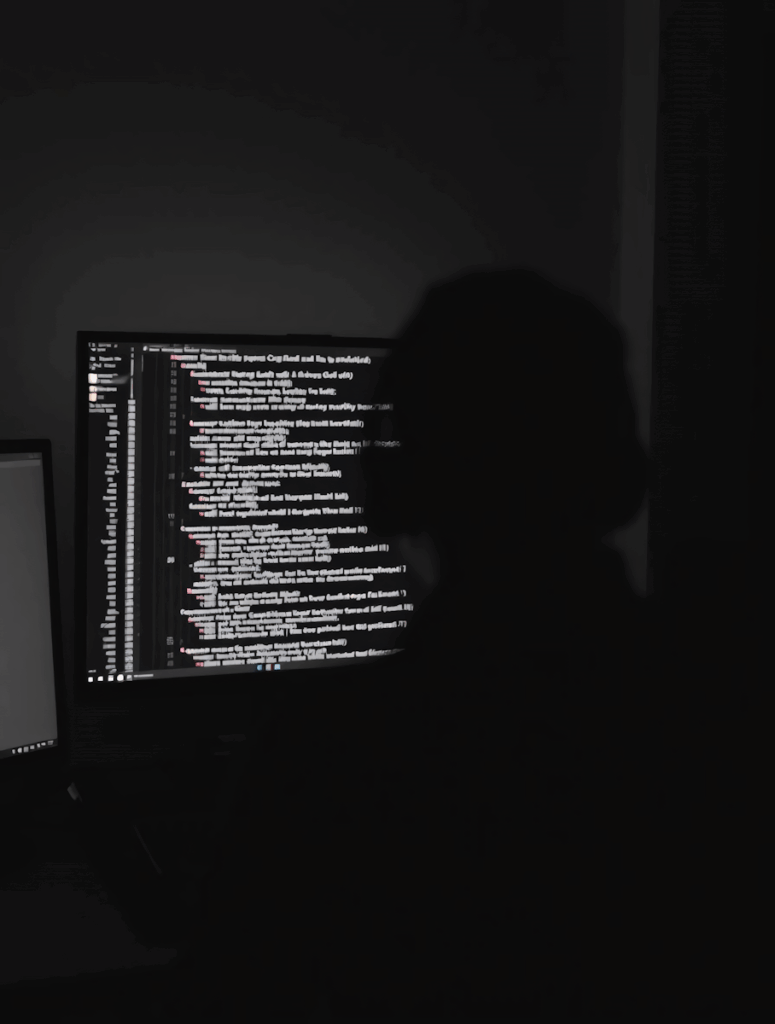 Almeida law group | a shadowed figure sits before a glowing monitor displaying lines of code