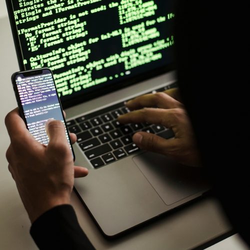Data-Breach-Featured-Image-2 Person coding on phone and laptop