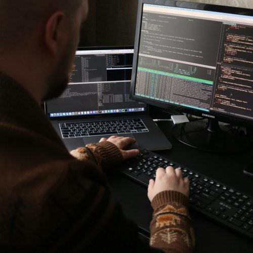 Man coding at computer and laptop